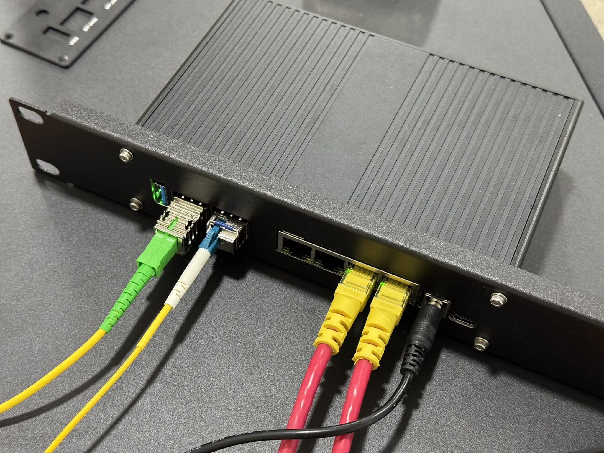 A bananapi-R4 switch, connected to fiber, rj45 and power cables. The S800E SFP module is visible, connected to a yellow/green patch cord